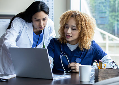 Young female nursing student being helped by her female instructor