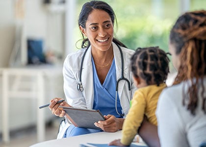 Smiling female nurse inquiring about the toddler patient in front of her